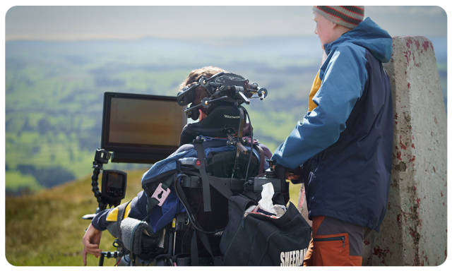 AAC user Oli with his device on top of a mountain