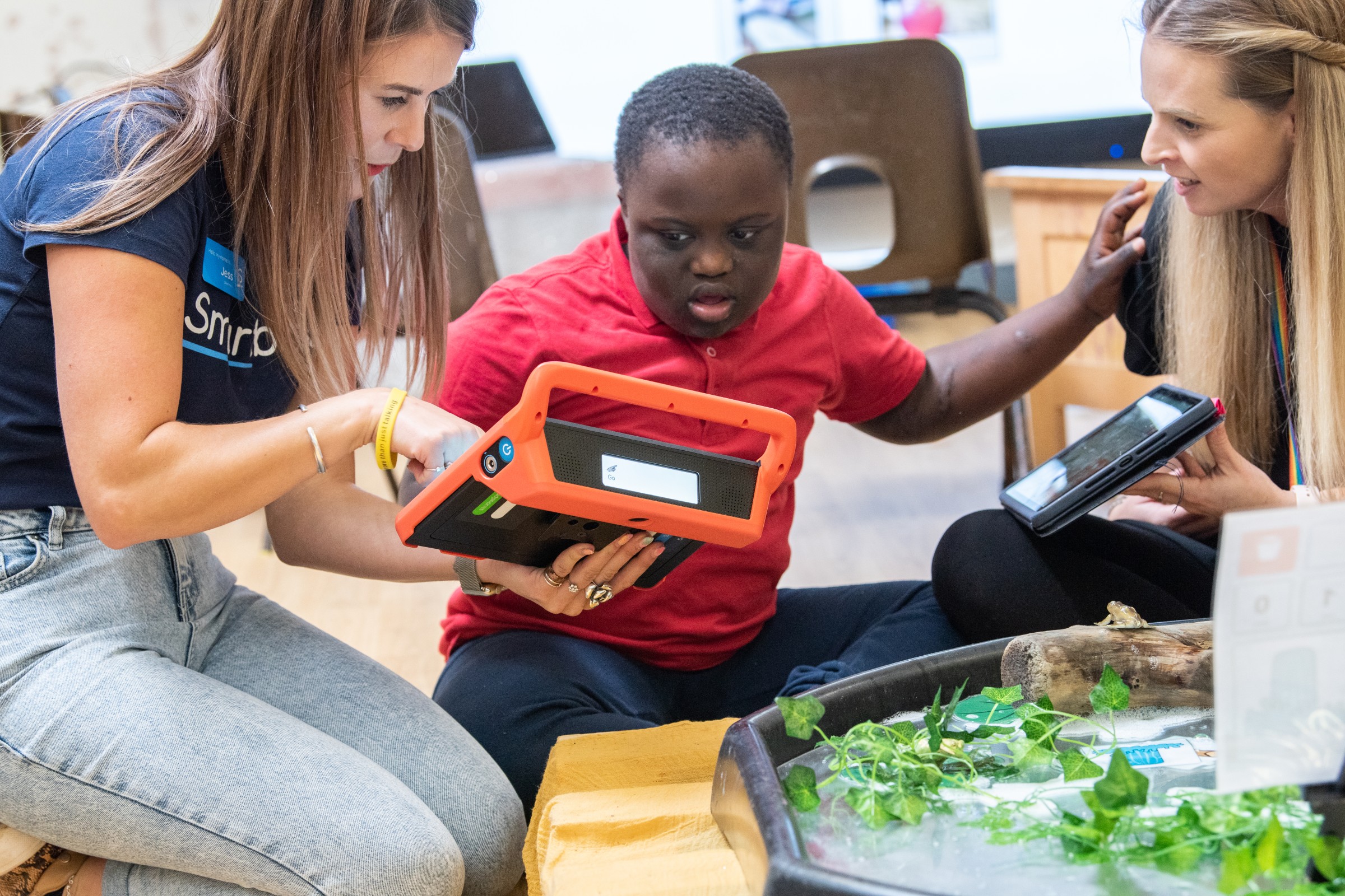 an AT Specialist and a teacher working with a child to use AAC