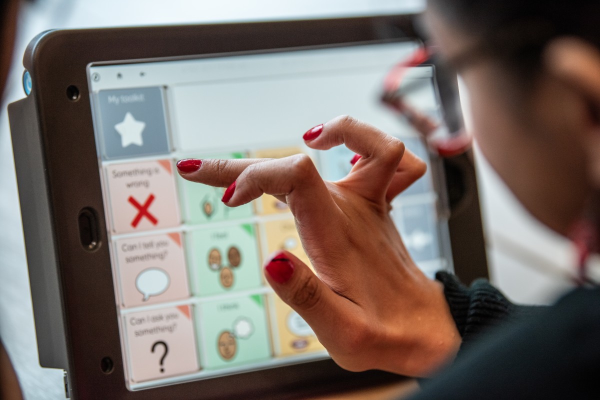 an AAC user touching a Talk Pad