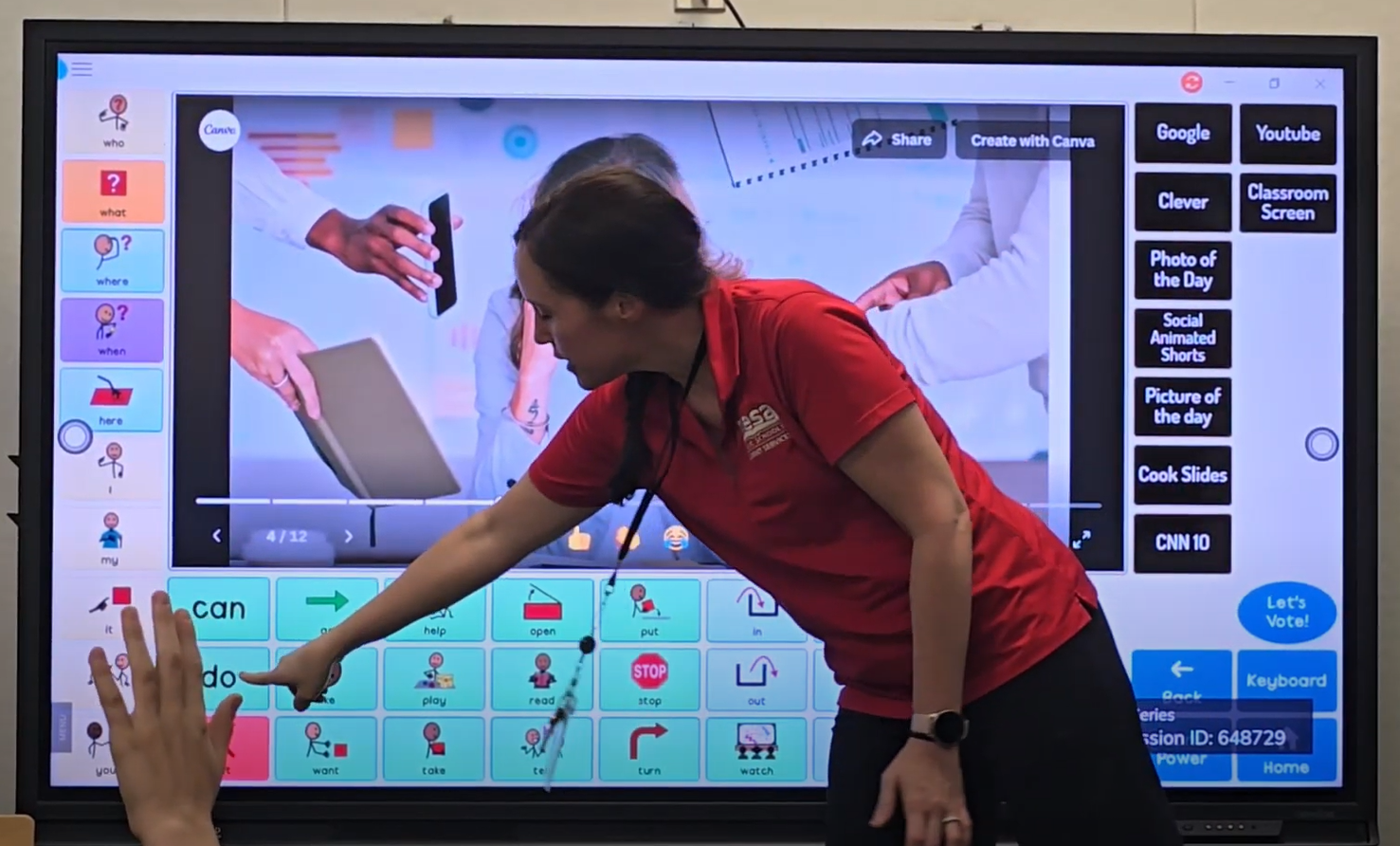 Teacher in a red shirt is standing at the front of the classroom in front of an interactive whiteboard with Grid on the screen. She is pointing to the word 