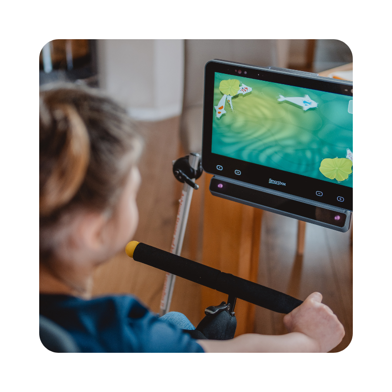 An eye gaze user looking at her AAC device, which has imagery of fish swimming in a pond on the screen.