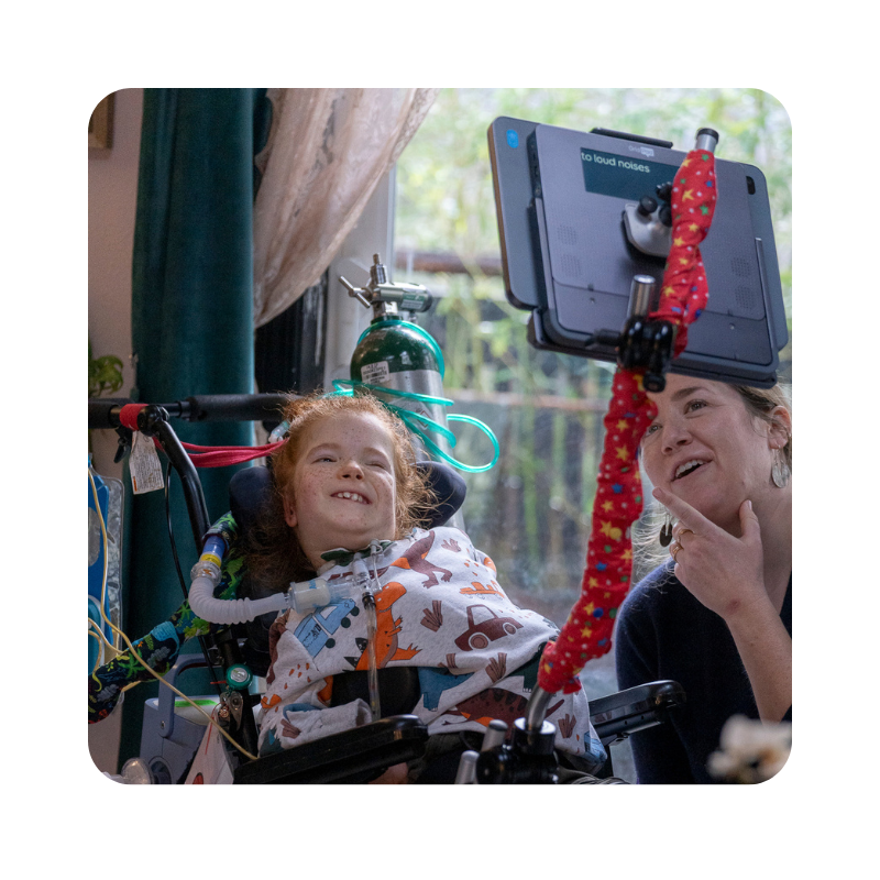 AAC user looking up at her device next to a communication partner