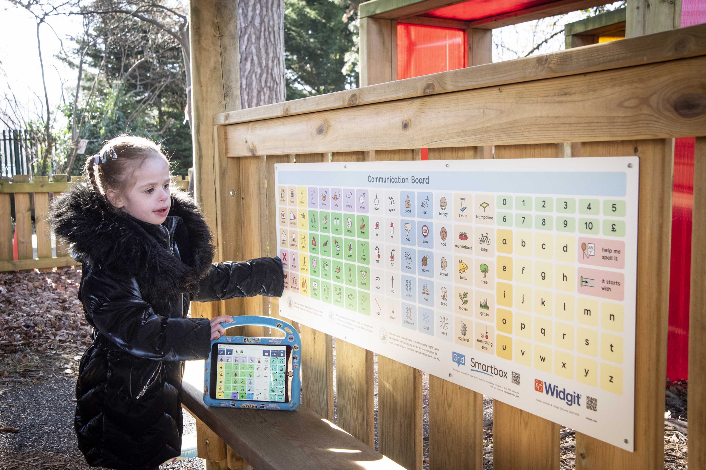 A young child with a communication aid looking at a Smartbox communication board.