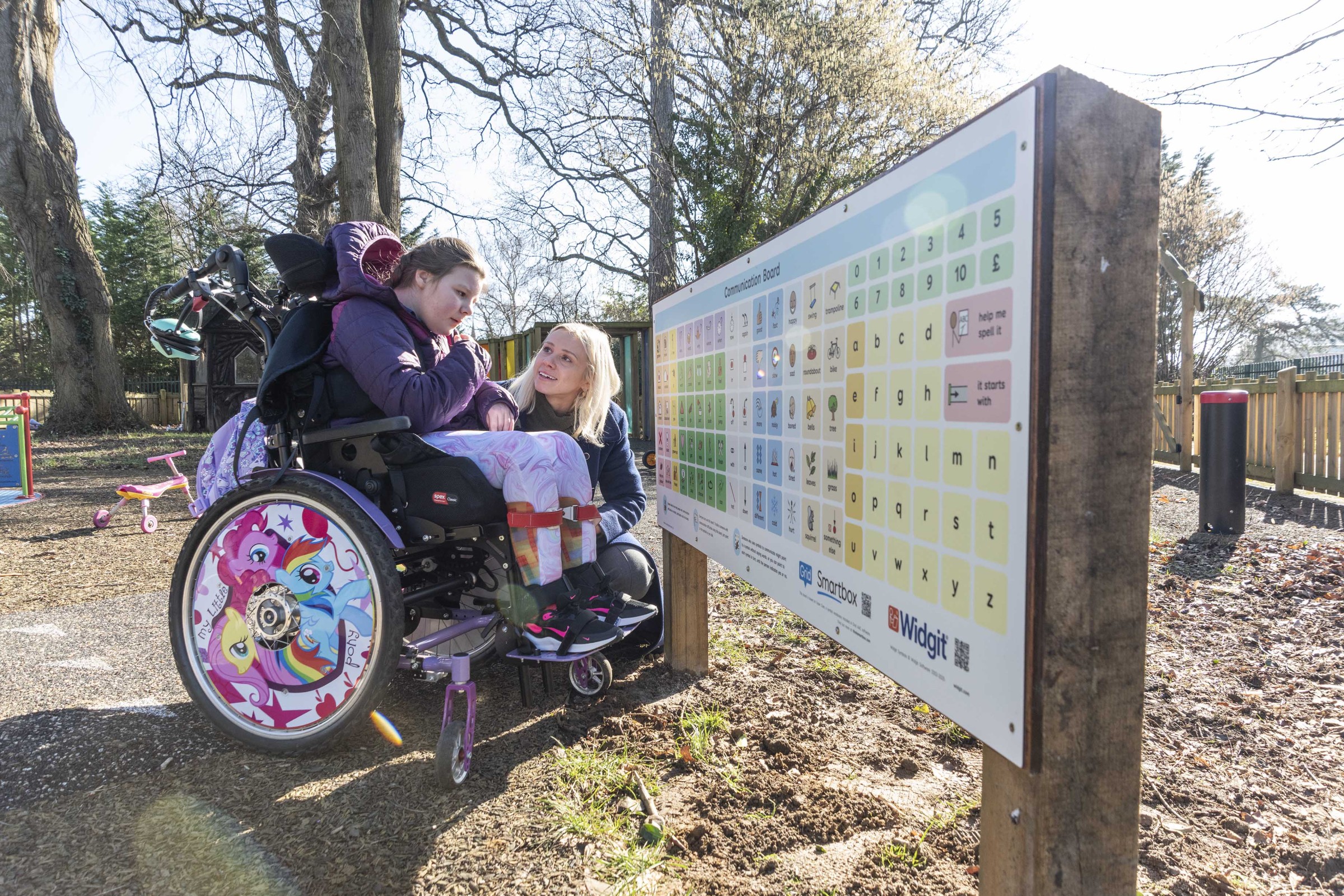 A young person in a wheelchair and a communication partner using the Smartbox communication board.